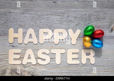 Foil covered Easter eggs on wooden background with the text "Happy Easter". Stock Photo