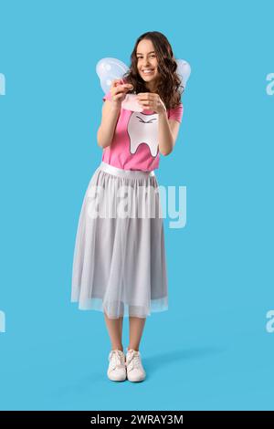 Tooth Fairy putting coin into wallet on blue background Stock Photo