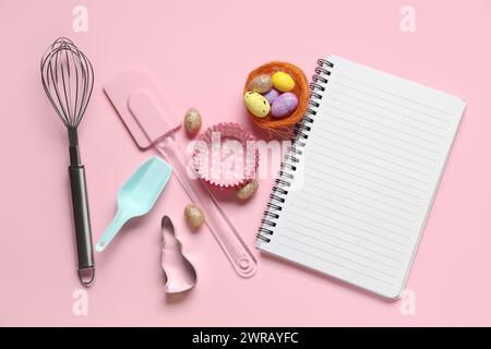 Blank notepad for recipes with Easter eggs and baking tools on pink background Stock Photo