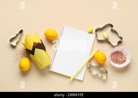 Blank notepad for recipes with pen, Easter eggs and baking tools on beige background Stock Photo