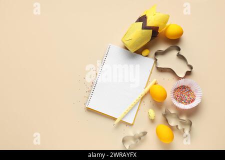 Blank notepad for recipes with pen, Easter eggs and baking tools on beige background Stock Photo
