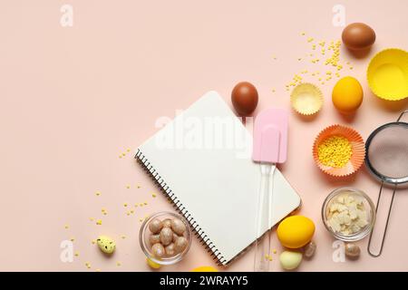 Blank notepad for recipes with Easter eggs and kitchen tools on beige background Stock Photo