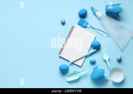 Blank notepad for recipes with pen, baking tools and Easter eggs on blue background Stock Photo
