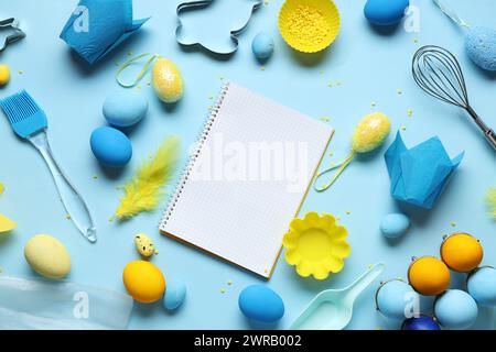 Blank notepad for recipes with baking tools and Easter eggs on blue background Stock Photo