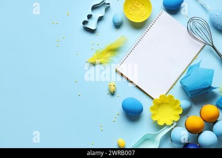 Blank notepad for recipes with baking tools and Easter eggs on blue background Stock Photo