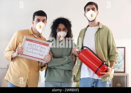 People in masks with evacuation plan and fire extinguisher in room Stock Photo