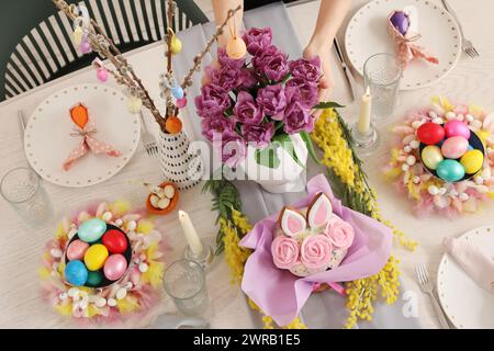 Beautiful Easter table setting with spring flowers, Easter cake and painted eggs Stock Photo