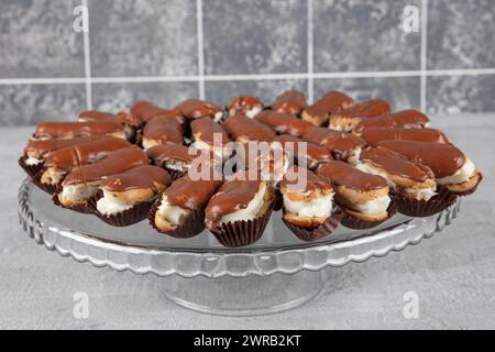 Eclairs with chocolate topping on serving plate. Traditional french eclairs with chocolate. Mini vanilla eclairs with chocolate frosting. Stock Photo