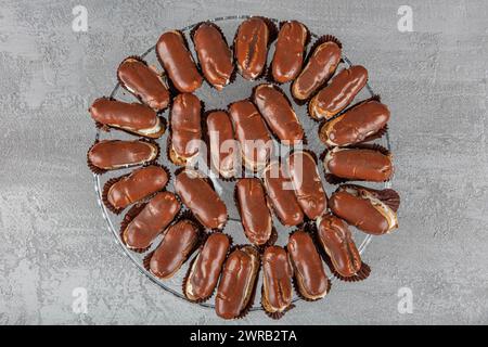 Eclairs with chocolate topping on serving plate. Traditional french eclairs with chocolate. Mini vanilla eclairs with chocolate frosting. Stock Photo