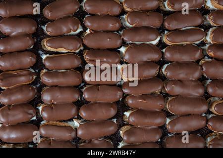 Eclairs with chocolate topping on serving plate. Traditional french eclairs with chocolate. Mini vanilla eclairs with chocolate frosting. Stock Photo