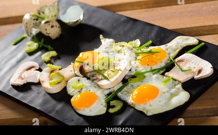 Broken fried quail eggs with mushrooms Stock Photo