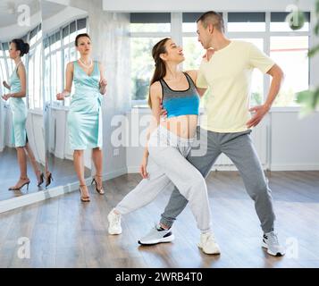 Couple practicing passionate tango guided by female dance instructor in studio Stock Photo