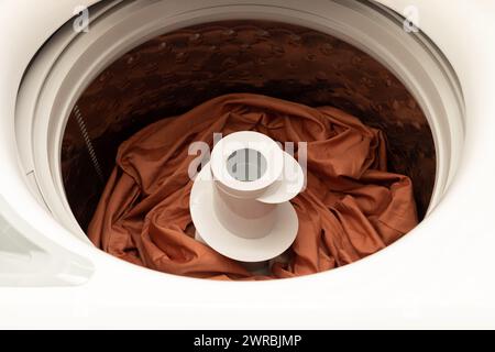 Top Loading Washing Machine With Colorful Bed Linen Inside. Laundry. Taking Care Of Colored Fabric, Apparel. Horizontal Plane Stock Photo