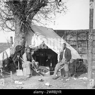 Culpeper, Va. 'Contrabands', Photograph from the main eastern theater of war, Meade in Virginia, August-November 1863. Shows two African American men sitting in front of a tent, one with cigar and the other with a soup ladle., O'Sullivan, Timothy H., 1840-1882, photographer, 1863 November., United States, History, Civil War, 1861-1865, Military life, Wet collodion negatives., Wet collodion negatives, 1 negative: glass, wet collodion Stock Photo