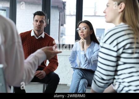 Psychotherapist working with patients in group therapy session indoors Stock Photo