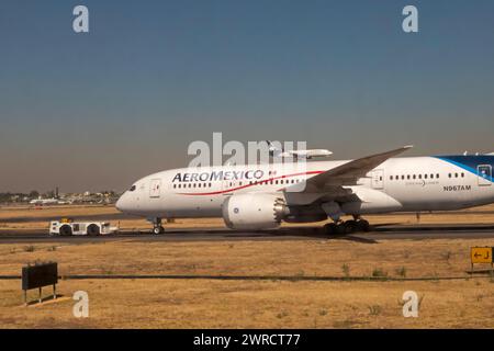 Mexico City - An AeroMexico Boeing 787-8 Dreamliner sits on the tarmac while another AeroMexico flight lands on a nearby runway. Stock Photo