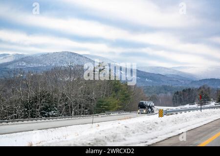 Industrial carrier car hauler blue big rig semi truck tractor transporting pick up trucks on the semi trailer driving on the winter highway road with Stock Photo