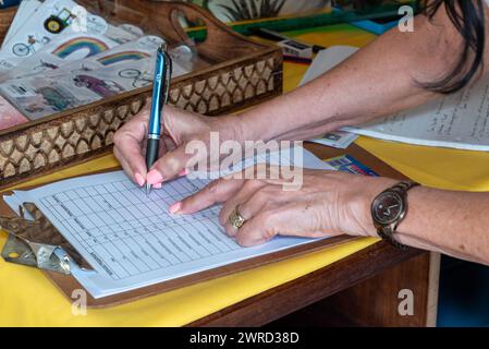 A woman's hands writing in a list on a clipboard Stock Photo
