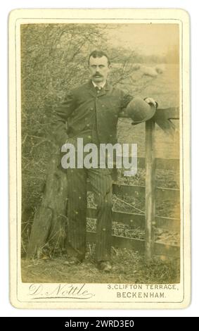 Original Victorian Carte de Visite (visiting card or CDV) handsome gent, in a suit holding a bowler hat, photographed in a rural setting, by field of sheep by D. Nottle of 3 Clifton Terrace, Beckenham, Kent, U.K. Circa 1880's Stock Photo