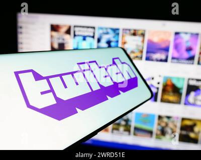 Cellphone with logo of American live streaming company Twitch Interactive Inc. in front of website. Focus on center-left of phone display. Stock Photo