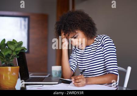 Woman, finance and thinking of problem at home, table with documents for tax and calculating debt. African female person, bills and stress of online Stock Photo