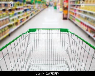 Supermarket interior, supermarket aisle with empty green shopping cart background, shopping in supermarket concept Stock Photo