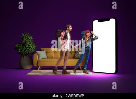 Young man and woman, couple with backpacks on back looking at giant 3D model screen, buying tickets online, choosing destination Stock Photo
