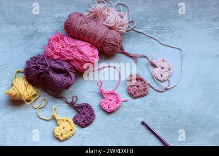 Soft cotton yarn, crochet hook and crochet project in process on grey stone background. Top view with copy space. Hobbies and leisure concept. Stock Photo