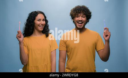 Multiracial couple Hispanic woman girl and Indian man Arabian guy holding tooth brush pretend brushing teeth dental care using toothbrushes oral Stock Photo