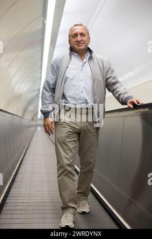 Middle aged man on moving walkway Stock Photo