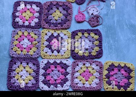 Handmade crocheted zigzag ornaments on grey background with copy space. Colorful cotton granny square. Crochet texture close up photo. Stock Photo