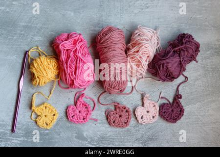 Soft cotton yarn, crochet hook and crochet project in process on grey stone background. Top view with copy space. Hobbies and leisure concept. Stock Photo