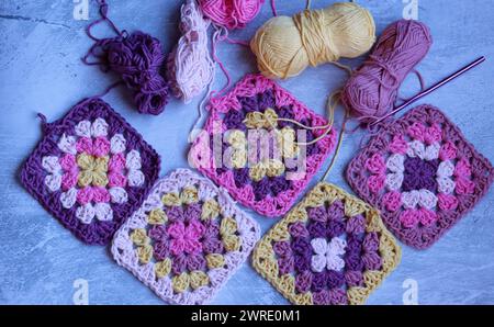 Handmade crocheted background. Colorful granny squares on light grey table. Stock Photo