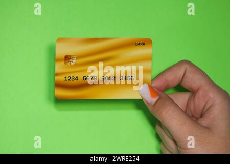 Close up female hand holds levitating template mockup Bank credit card with online service isolated on green background. High quality photo Stock Photo