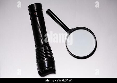 The picture shows a magnifying glass and a flashlight, which is necessary to have in your bag while you are going camping in nature. Stock Photo