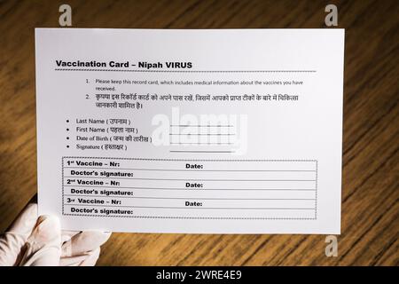 The picture shows how a doctor holds the new vaccination card against the new Nipah virus. On a wooden background. Stock Photo