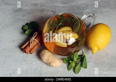 Still life with glass teapot, lemons and mint leaves on a table. Healthy homemade drink closes up photo. Stock Photo