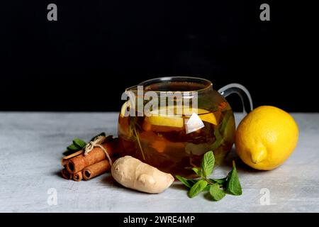 Still life with glass teapot, lemons and mint leaves on a table. Healthy homemade drink closes up photo. Stock Photo