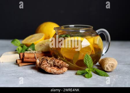 Still life with glass teapot, lemons and mint leaves on a table. Healthy homemade drink closes up photo. Stock Photo