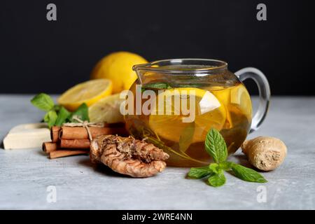 Still life with glass teapot, lemons and mint leaves on a table. Healthy homemade drink closes up photo. Stock Photo