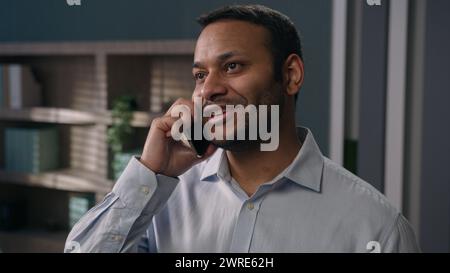 Smiling Arabian Indian business man talking mobile phone distant negotiate sales talk communicate with colleagues consult client in office businessman Stock Photo