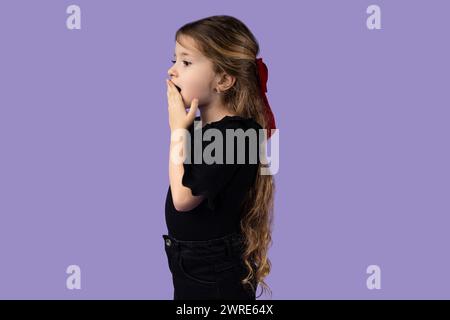 Horizontal photo of a little girl on a purple background who is shocked by something, and looks to the side, picture for promotion of discount ads or Stock Photo