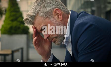 Pensive Caucasian middle-aged old man thinking thoughtful sad unwell anxious senior businessman solving problem headache migraine worry career failure Stock Photo