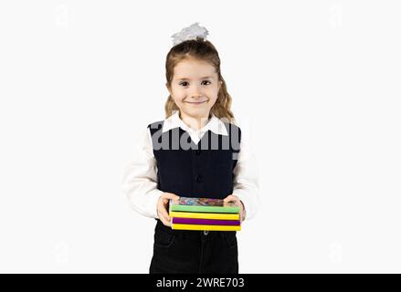 A happy toddler in a school uniform and electric blue sleeve holding a stack of books with a smile, formal wear and waist gesture Stock Photo