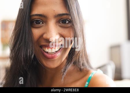 Young biracial woman with a bright smile, wearing a green top Stock Photo
