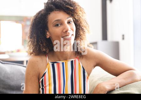 Biracial woman with curly hair smiles, wearing a striped top Stock Photo