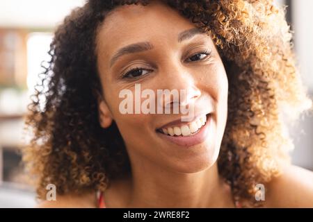 Biracial woman with curly hair smiles warmly, her brown eyes gleaming Stock Photo