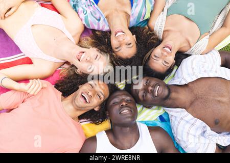 Diverse group of friends lying down close together, smiling at the camera Stock Photo