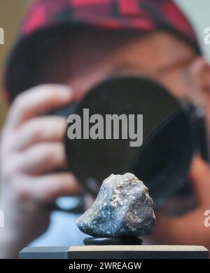 Berlin, Germany. 12th Mar, 2024. A photographer takes a picture of one of the fragments of a meteorite in the Mineral Hall of the Museum of Natural History. The meteorite hit the earth near Ribbeck near Berlin in January. Credit: Soeren Stache/dpa/Alamy Live News Stock Photo