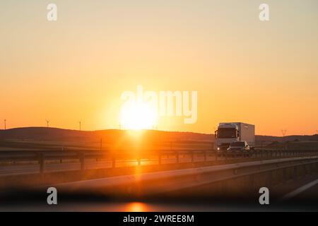 Truck driving on highway at sunset, with afterglow in sky Stock Photo